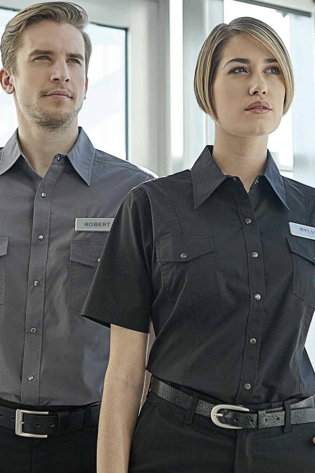 Une femme et un homme oeuvrant en entretien et portant des uniformes de travail du magasin Uniformes Town & Country, à Laval